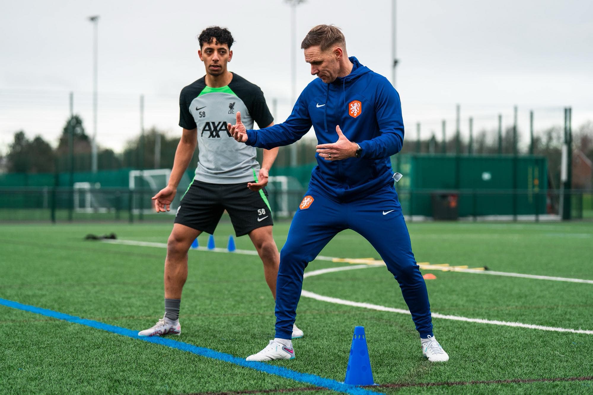 Professional football coach demonstrating technique to a Liverpool FC player during training session